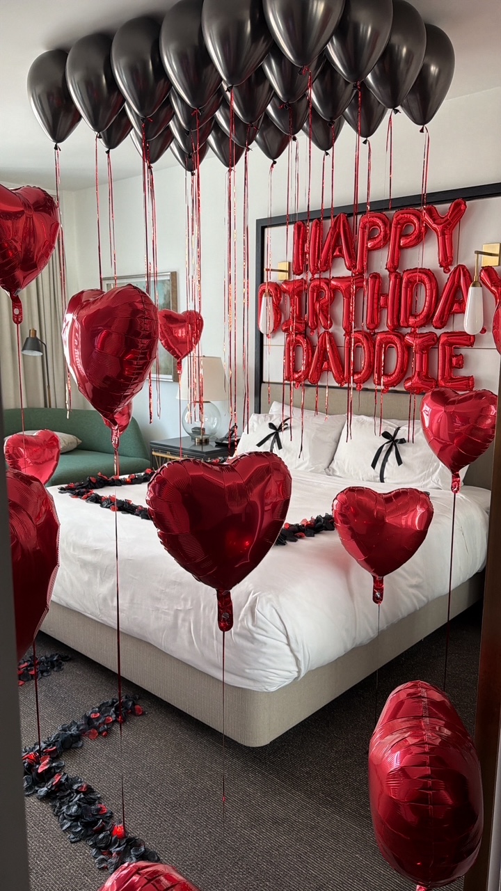Suite styled with red heart balloons, black ceiling balloons and a rose petal path